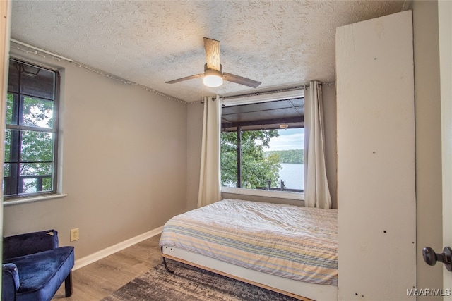 bedroom featuring wood-type flooring, a textured ceiling, and ceiling fan