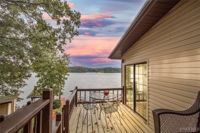 deck at dusk featuring a water view