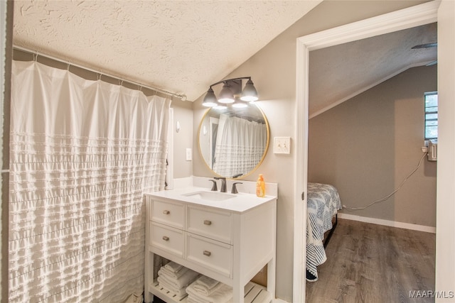 bathroom featuring lofted ceiling, a textured ceiling, hardwood / wood-style flooring, and vanity