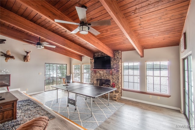 interior space featuring ceiling fan, vaulted ceiling with beams, wood ceiling, light hardwood / wood-style flooring, and a fireplace