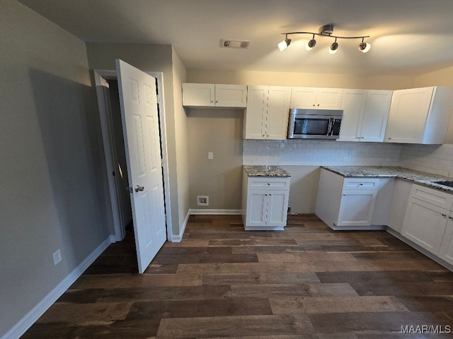 1780 Fitzpatrick Rd, Wetumpka, AL 36092 - kitchen featuring stainless steel microwave, dark wood finished floors, backsplash, visible vents, and white cabinets