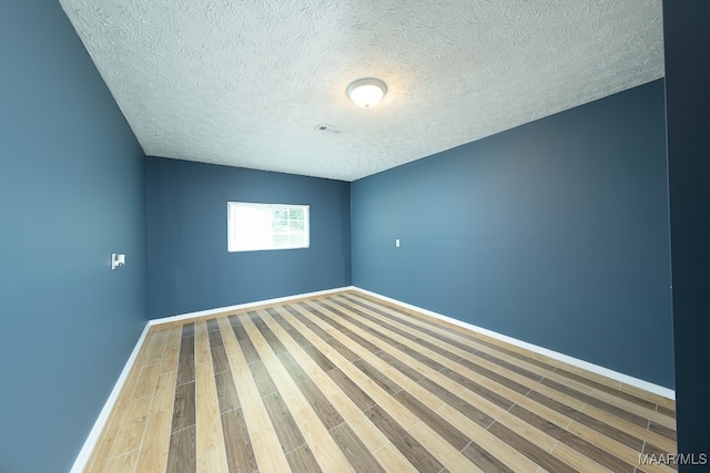 empty room with wood-type flooring and a textured ceiling