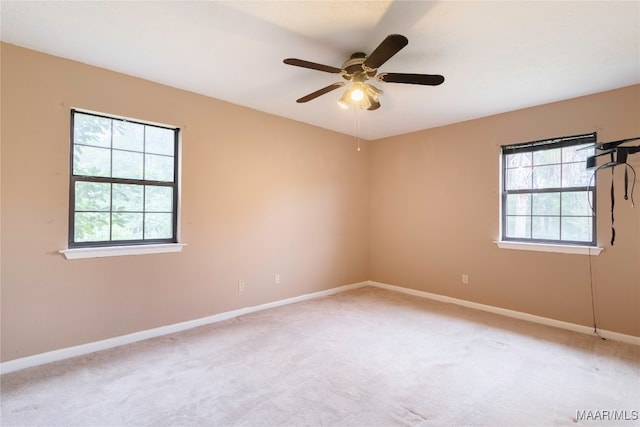 spare room featuring carpet, ceiling fan, and a wealth of natural light