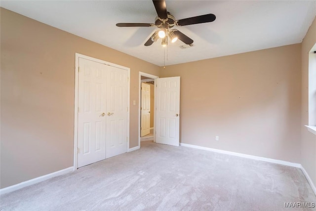 unfurnished bedroom featuring ceiling fan, visible vents, baseboards, a closet, and light carpet