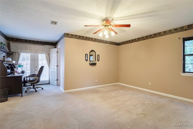 carpeted office space featuring ceiling fan, a textured ceiling, french doors, and a wealth of natural light