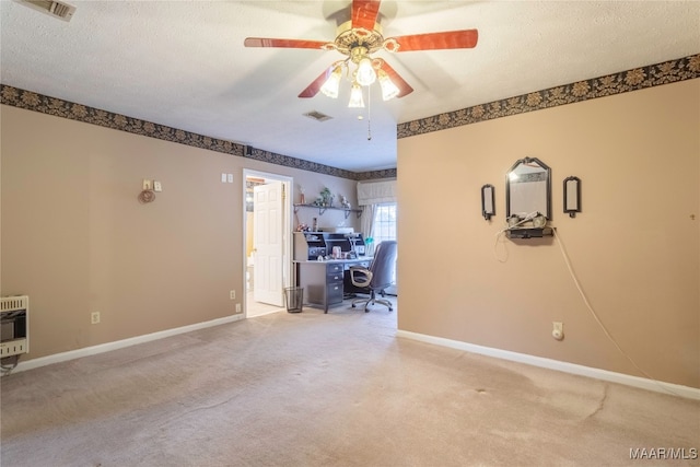 unfurnished office with carpet floors, a textured ceiling, ceiling fan, and heating unit