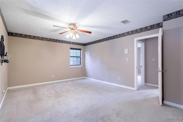 empty room featuring baseboards, light carpet, a ceiling fan, and a textured ceiling