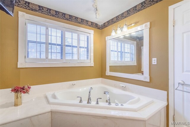 bathroom with a tub and rail lighting