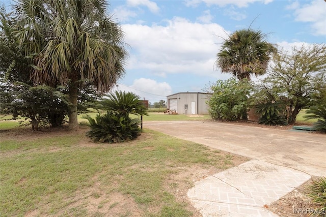 view of yard with an outbuilding, driveway, and a detached garage