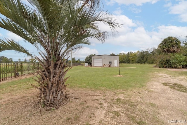 view of yard with fence, a detached garage, and an outdoor structure
