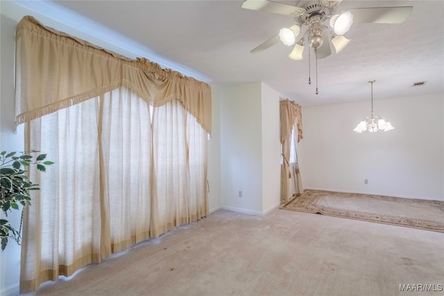 carpeted empty room with ceiling fan with notable chandelier