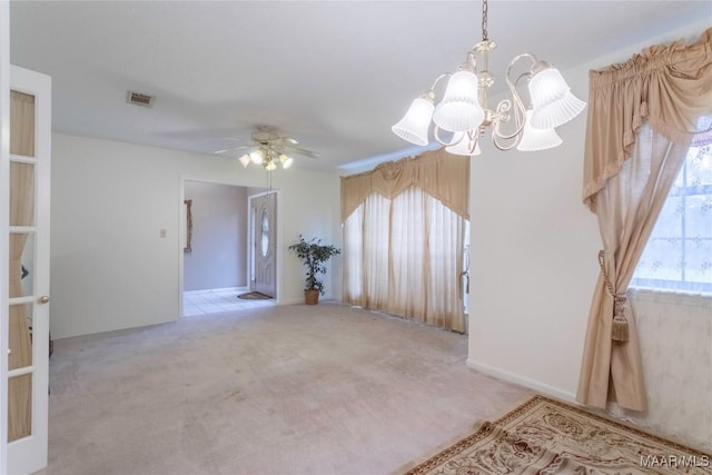 carpeted empty room featuring ceiling fan with notable chandelier and visible vents