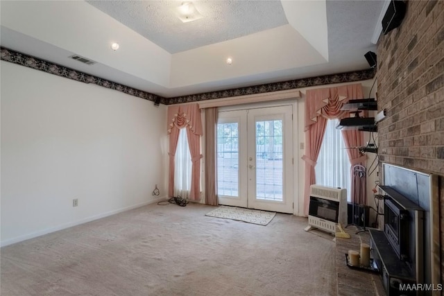 unfurnished living room with carpet flooring, a textured ceiling, french doors, heating unit, and visible vents