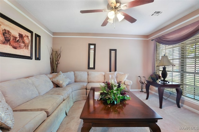 carpeted living room featuring ornamental molding and ceiling fan