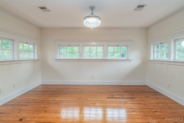 unfurnished room featuring light hardwood / wood-style flooring, crown molding, and a chandelier