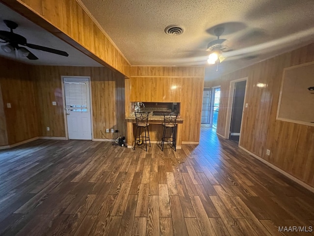 kitchen featuring ceiling fan, a textured ceiling, dark hardwood / wood-style floors, and a breakfast bar