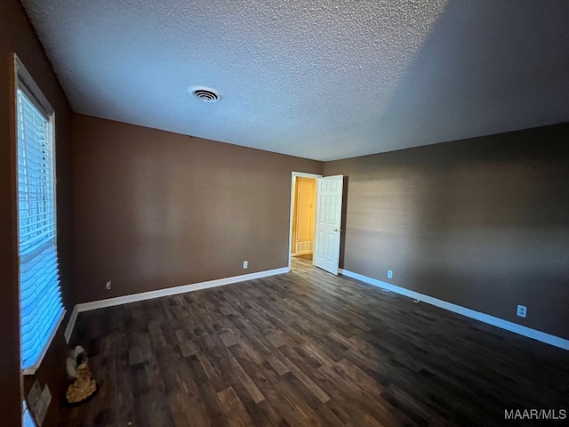 empty room featuring a textured ceiling and dark hardwood / wood-style floors