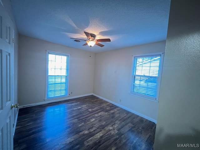 spare room featuring a wealth of natural light, ceiling fan, and dark wood-type flooring