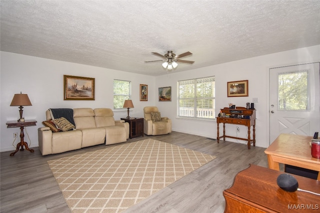 living room with ceiling fan, hardwood / wood-style flooring, plenty of natural light, and a textured ceiling