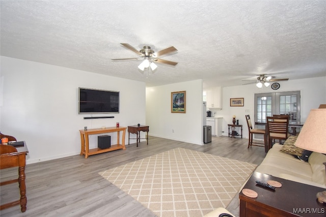 living room featuring light wood-type flooring, a textured ceiling, ceiling fan, and french doors