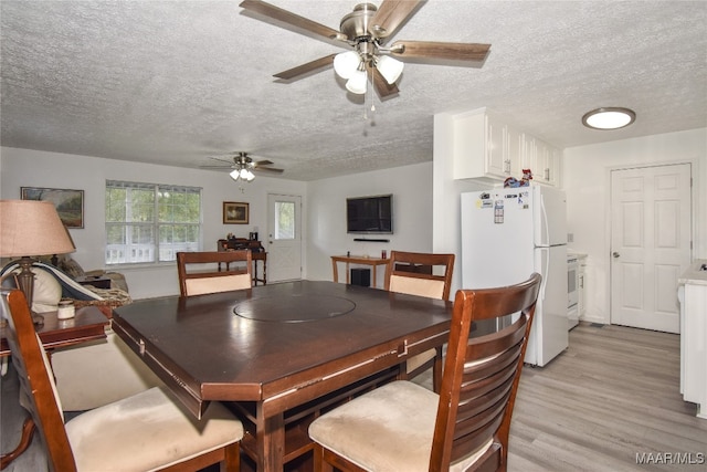 dining area with light wood-type flooring, a textured ceiling, and ceiling fan