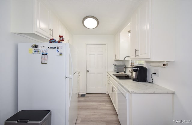 kitchen with white cabinetry, light stone counters, white appliances, light hardwood / wood-style flooring, and sink