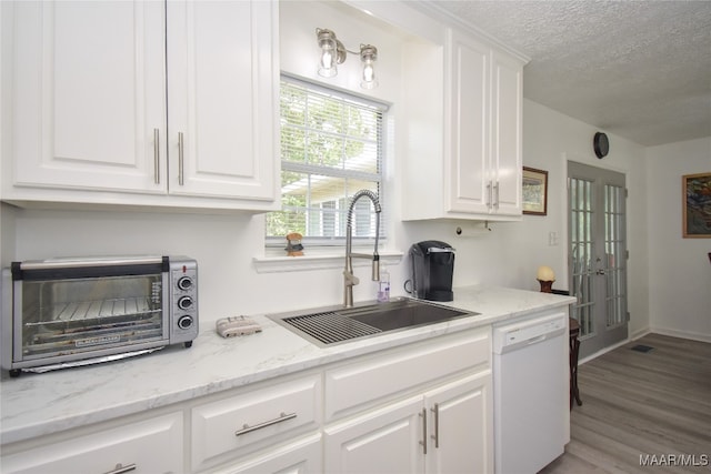 kitchen with white cabinetry, light stone countertops, white dishwasher, light wood-type flooring, and sink