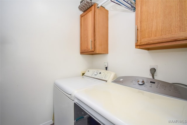 clothes washing area featuring cabinets and washer and clothes dryer