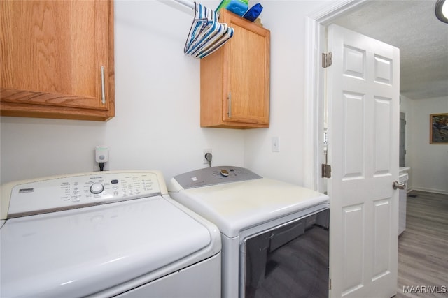 washroom featuring cabinets, hardwood / wood-style flooring, a textured ceiling, and washing machine and dryer