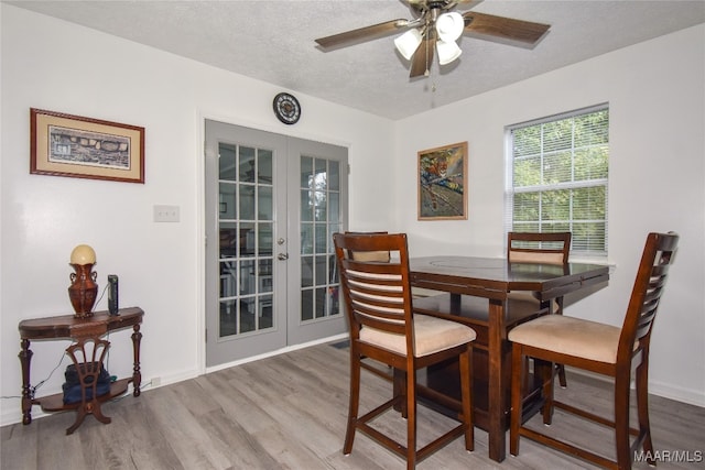 dining room featuring french doors, ceiling fan, hardwood / wood-style floors, and a textured ceiling