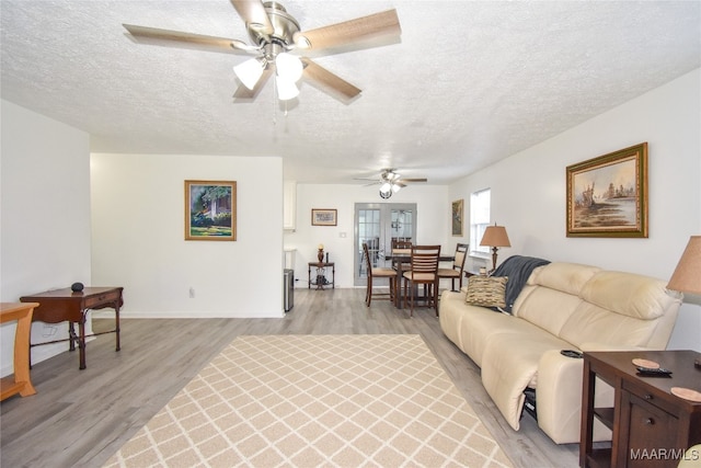 living room featuring light wood-type flooring, a textured ceiling, and ceiling fan