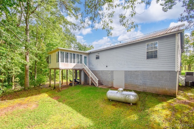 rear view of property featuring a lawn and a sunroom