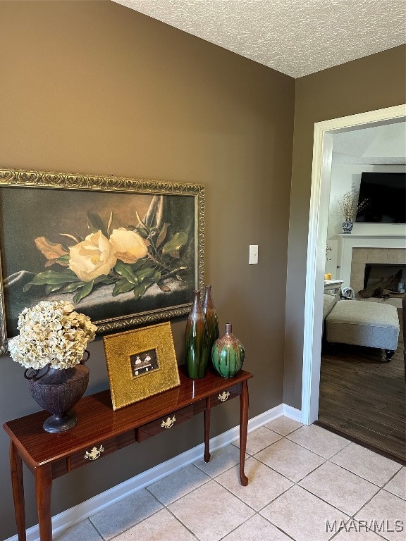 interior space with tile patterned flooring, a tiled fireplace, and a textured ceiling