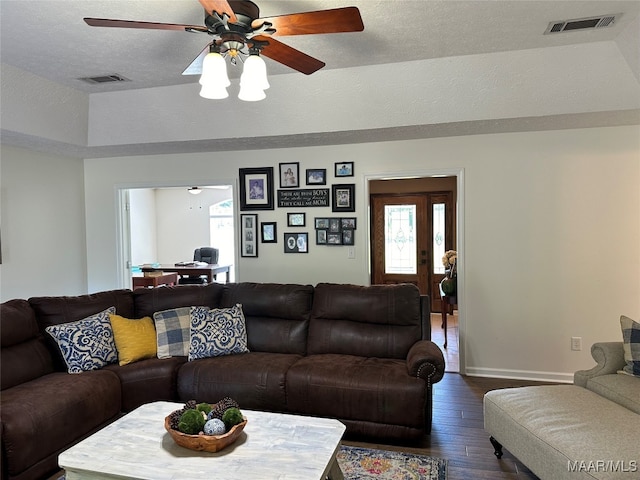 living room with ceiling fan, vaulted ceiling, a textured ceiling, and dark hardwood / wood-style flooring