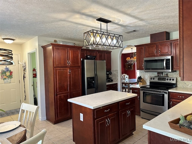 kitchen with pendant lighting, a center island, light tile patterned flooring, backsplash, and appliances with stainless steel finishes