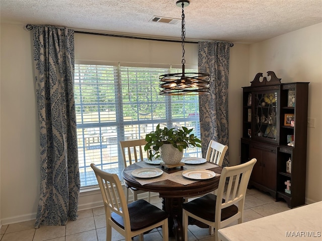 dining room with a notable chandelier, light tile patterned floors, and a textured ceiling