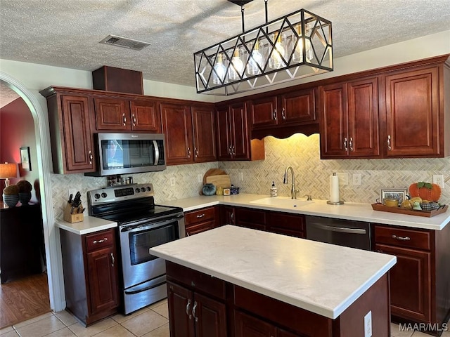 414 Warrior Dr, Valley Grande, AL 36701 - kitchen with appliances with stainless steel finishes, a sink, light countertops, hanging light fixtures, and arched walkways