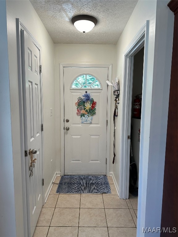 doorway to outside featuring a textured ceiling and light tile patterned floors