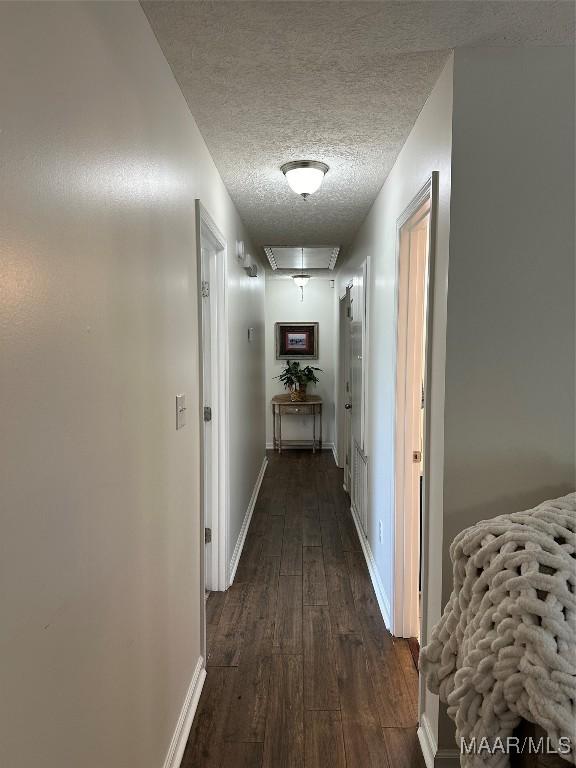 414 Warrior Dr, Valley Grande, AL 36701 - hall featuring dark wood-style floors, a textured ceiling, attic access, and baseboards