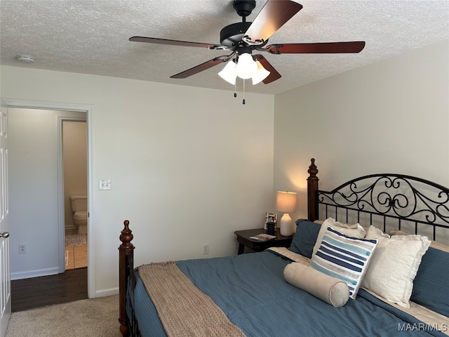 bedroom with a textured ceiling, connected bathroom, ceiling fan, and light colored carpet