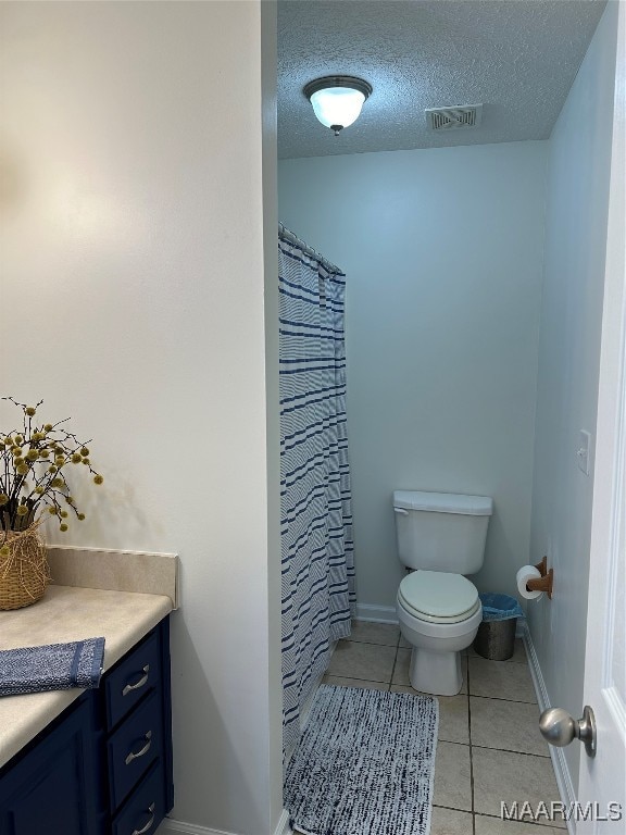 bathroom featuring tile patterned flooring, a textured ceiling, walk in shower, vanity, and toilet