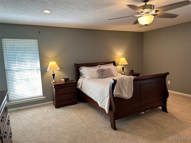 bedroom with ceiling fan, light colored carpet, and a textured ceiling