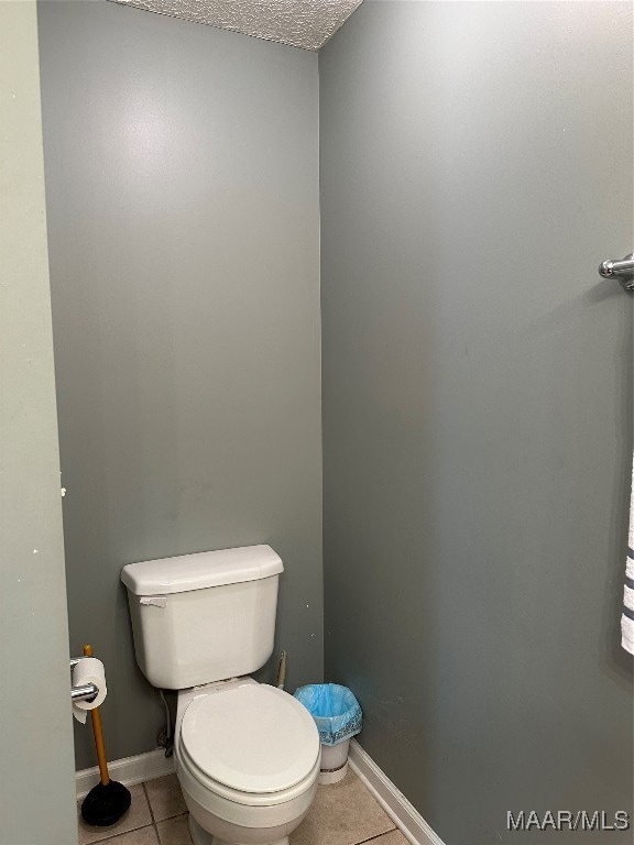 bathroom featuring a textured ceiling, toilet, and tile patterned floors