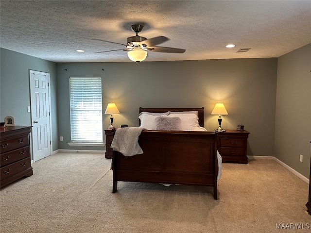 bedroom featuring light carpet, ceiling fan, and a textured ceiling