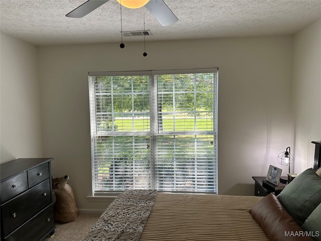 carpeted bedroom featuring ceiling fan and a textured ceiling