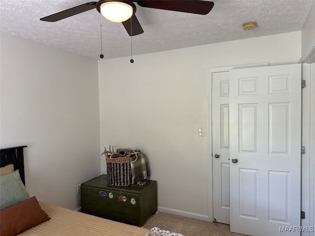 carpeted bedroom with ceiling fan, a textured ceiling, and a closet