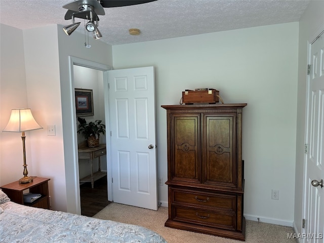 bedroom featuring light carpet, ceiling fan, and a textured ceiling