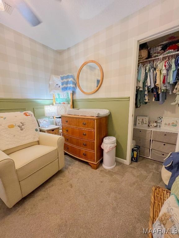 bedroom featuring wallpapered walls, a closet, a wainscoted wall, and light colored carpet