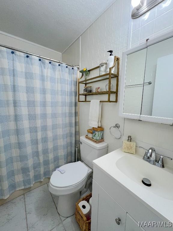 full bathroom featuring toilet, marble finish floor, a textured ceiling, vanity, and tile walls