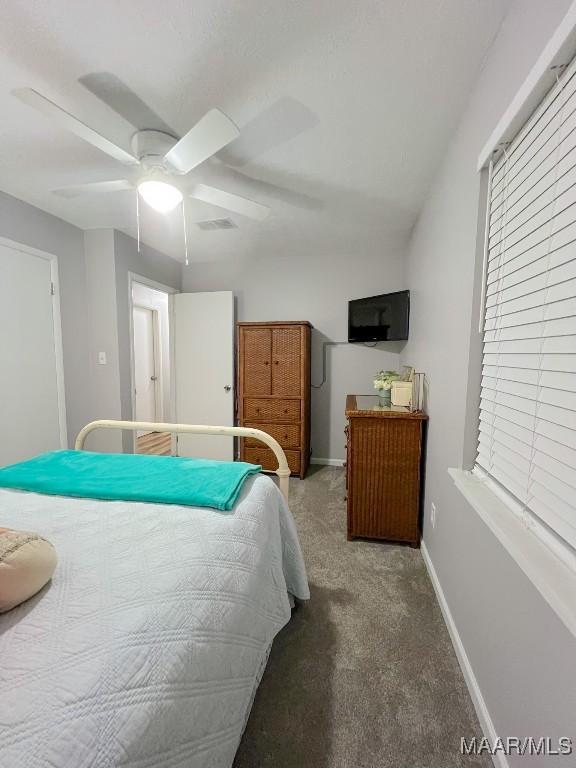 bedroom with ceiling fan, dark carpet, visible vents, and baseboards